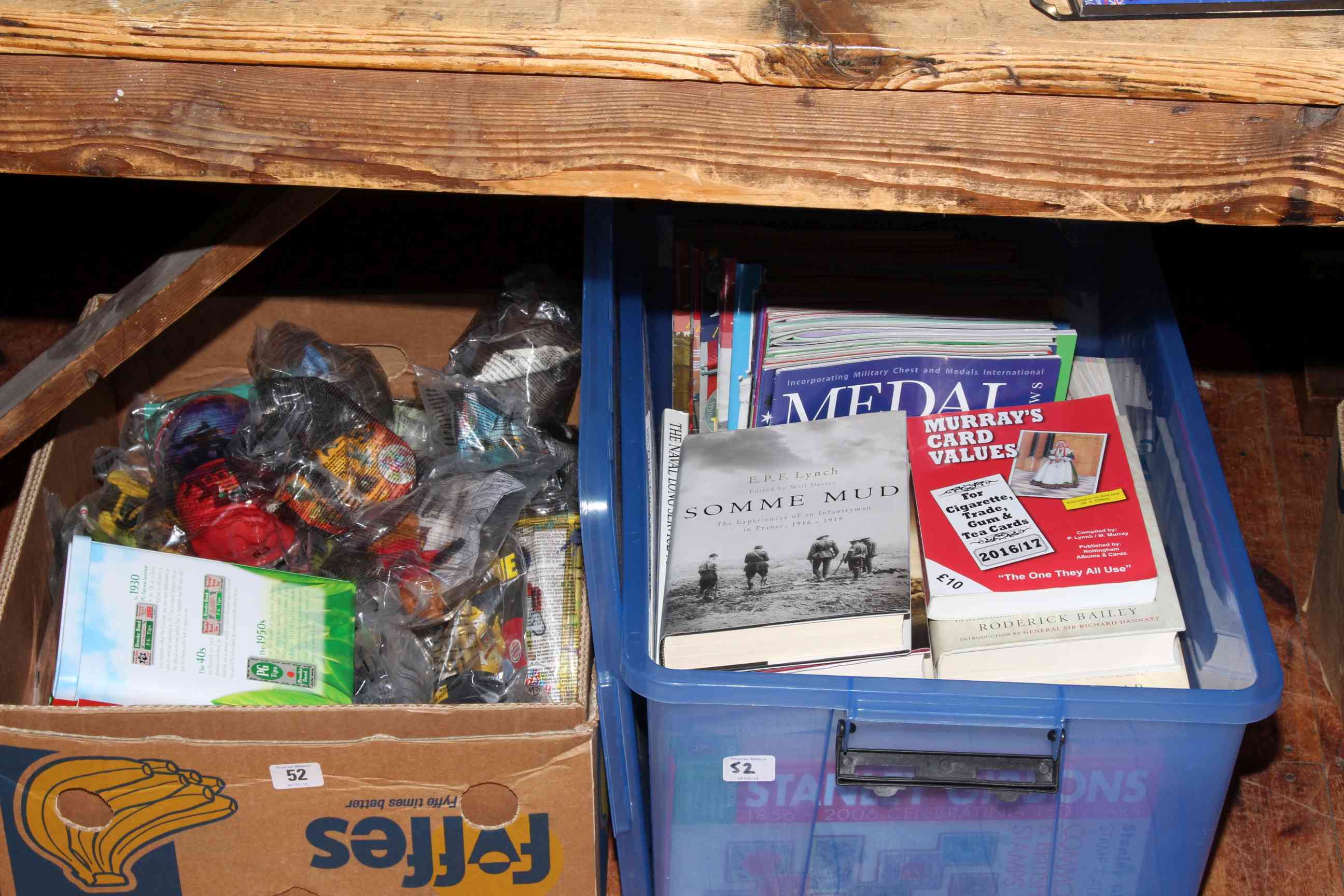 Box of McDonald's bagged toys and a box of military and reference books.