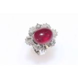 14 carat white gold, ruby and diamond ballerina style cluster ring featuring oval cabochon ruby,