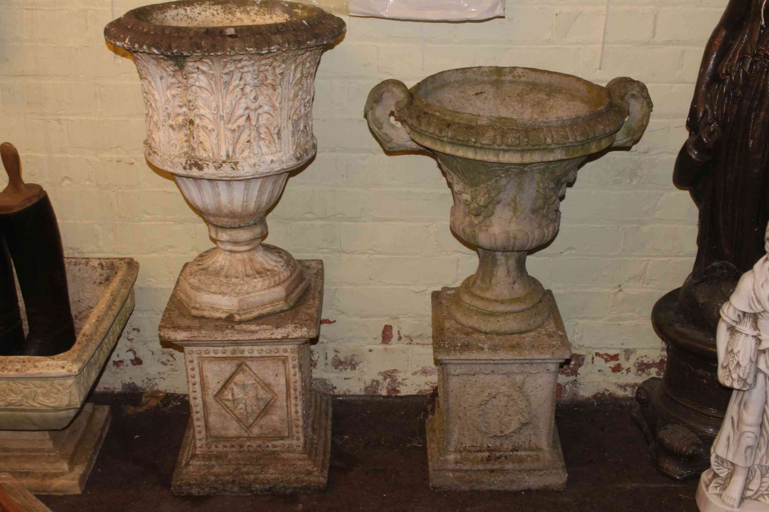 Two weathered garden urns on stands.