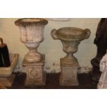 Two weathered garden urns on stands.