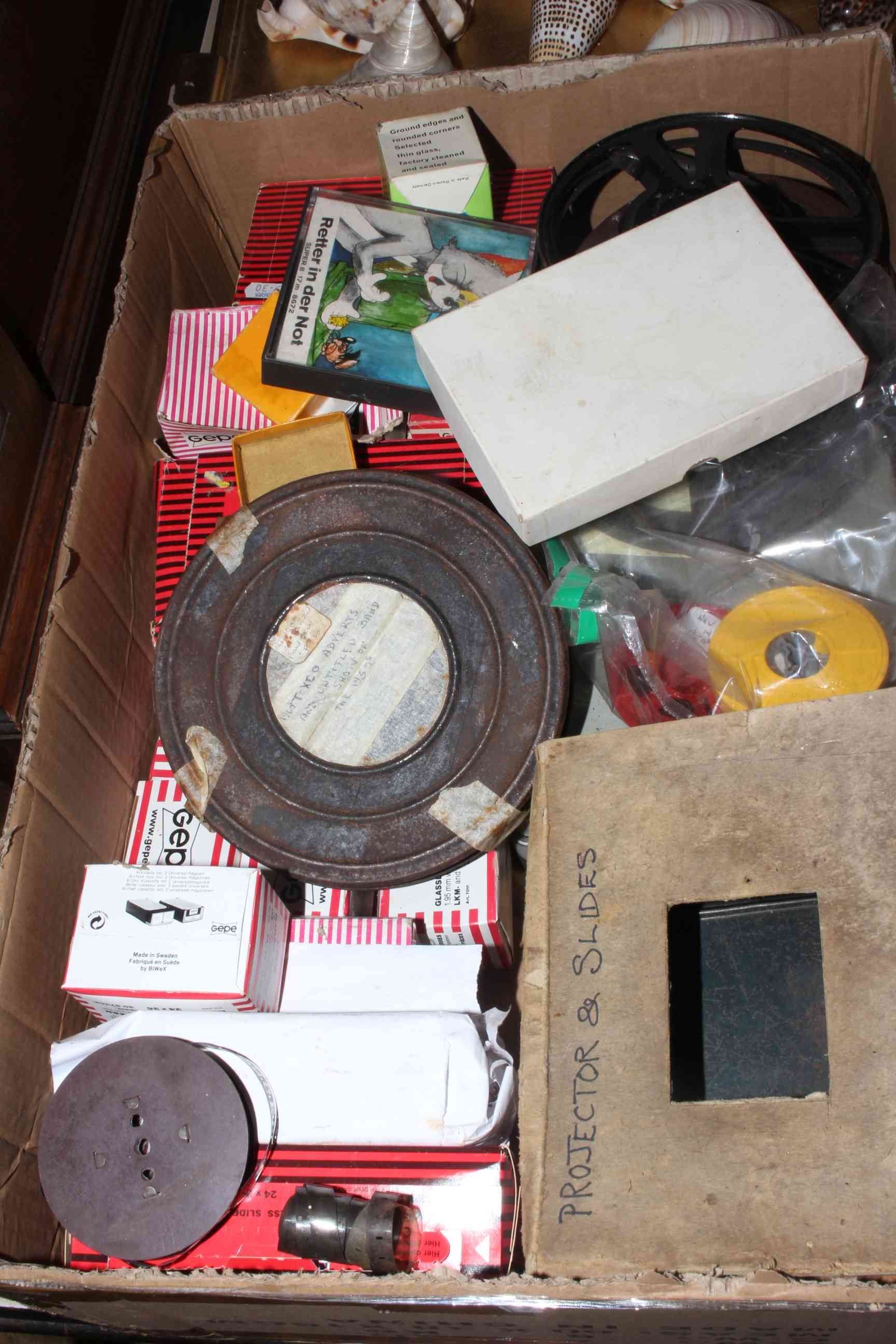 Box with vintage projector, slides and film reels.