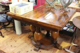 Oak draw leaf dining table raised on four central bulbous legs.