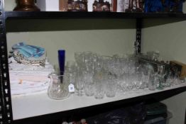 Shelf lot of glass, linens and crystal.