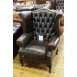 Brown deep buttoned back leather wing armchair.