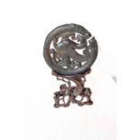Chinese black jade (?) pierced roundel with dragon and border of serpents, carved wood stand,