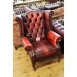 Ox blood deep buttoned back leather wing armchair.