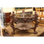 Heavily carved oak glass top coffee table with lion masks and griffins, raised on three paw feet.