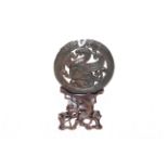 Chinese black jade roundel with dragon and border of serpents on wood stand, 10.5cm.