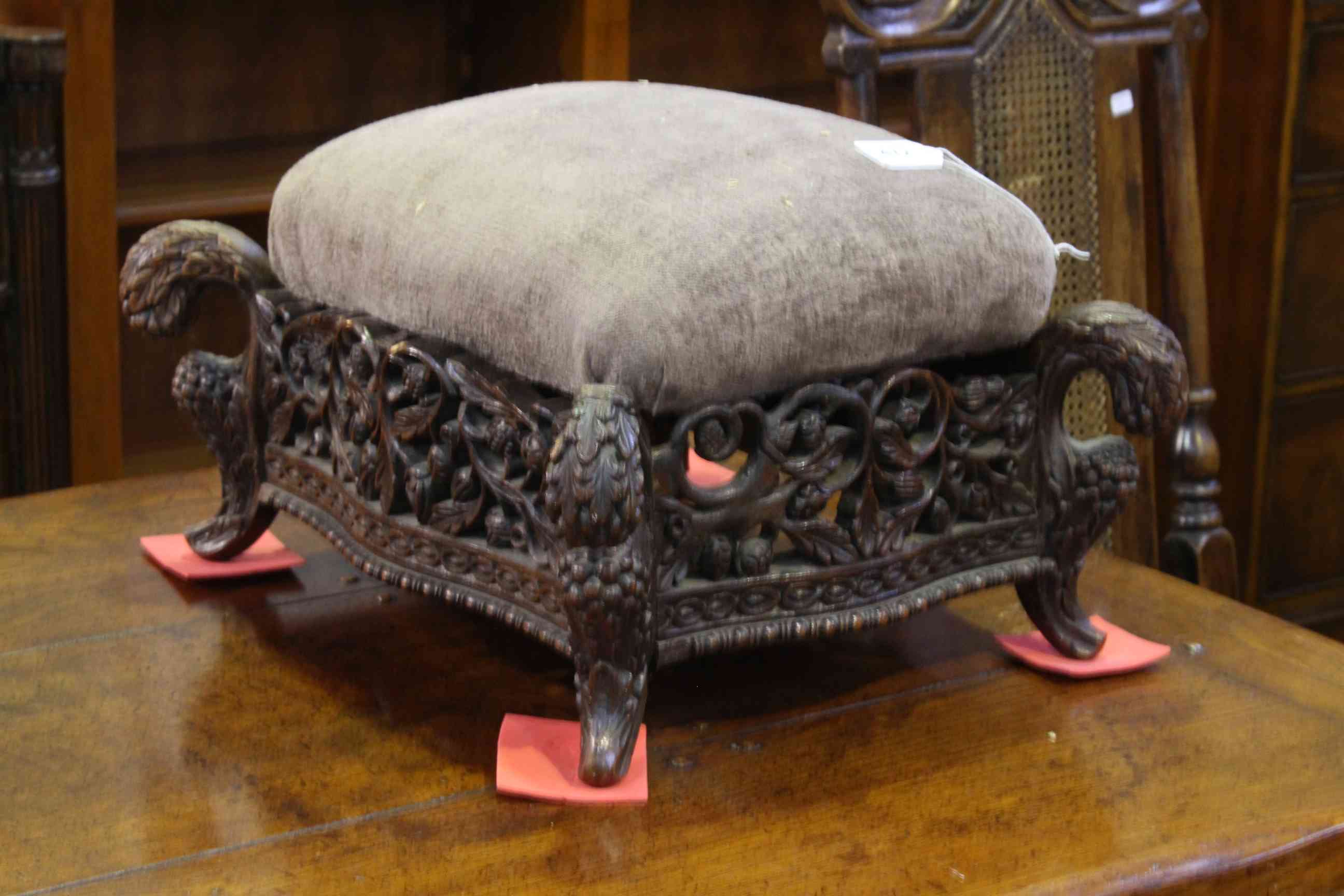 Ornate carved hardwood footstool with serpentine sided with upholstered top.