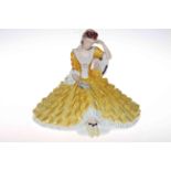 Large Royal Dux figurine of seated lady in yellow dress.