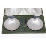 Cased pair of silver shell shaped butter dishes and knives, Sheffield 1911.