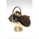 Polished embossed brass swing handled coal scuttle with integrated shovel.