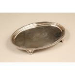 George III silver salver of oval form, gadrooned rim engraved coat of arms, raised on four scroll