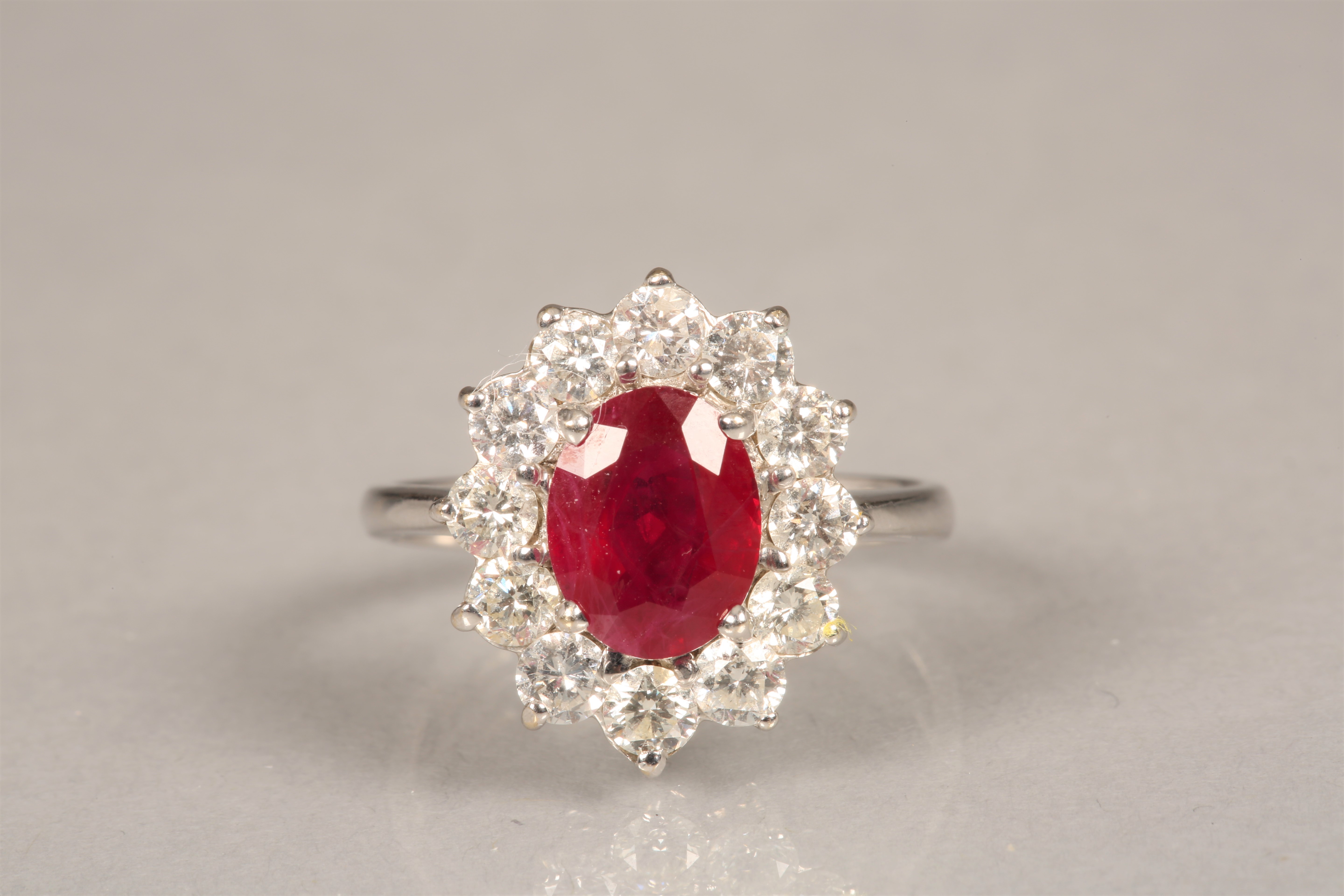 Ladies 18 carat white gold ruby and diamond ring, central ruby surrounded by twelve 0.1 carat