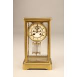 French brass cased four glass clock, white circular dial with black Roman numerals, bevelled glass
