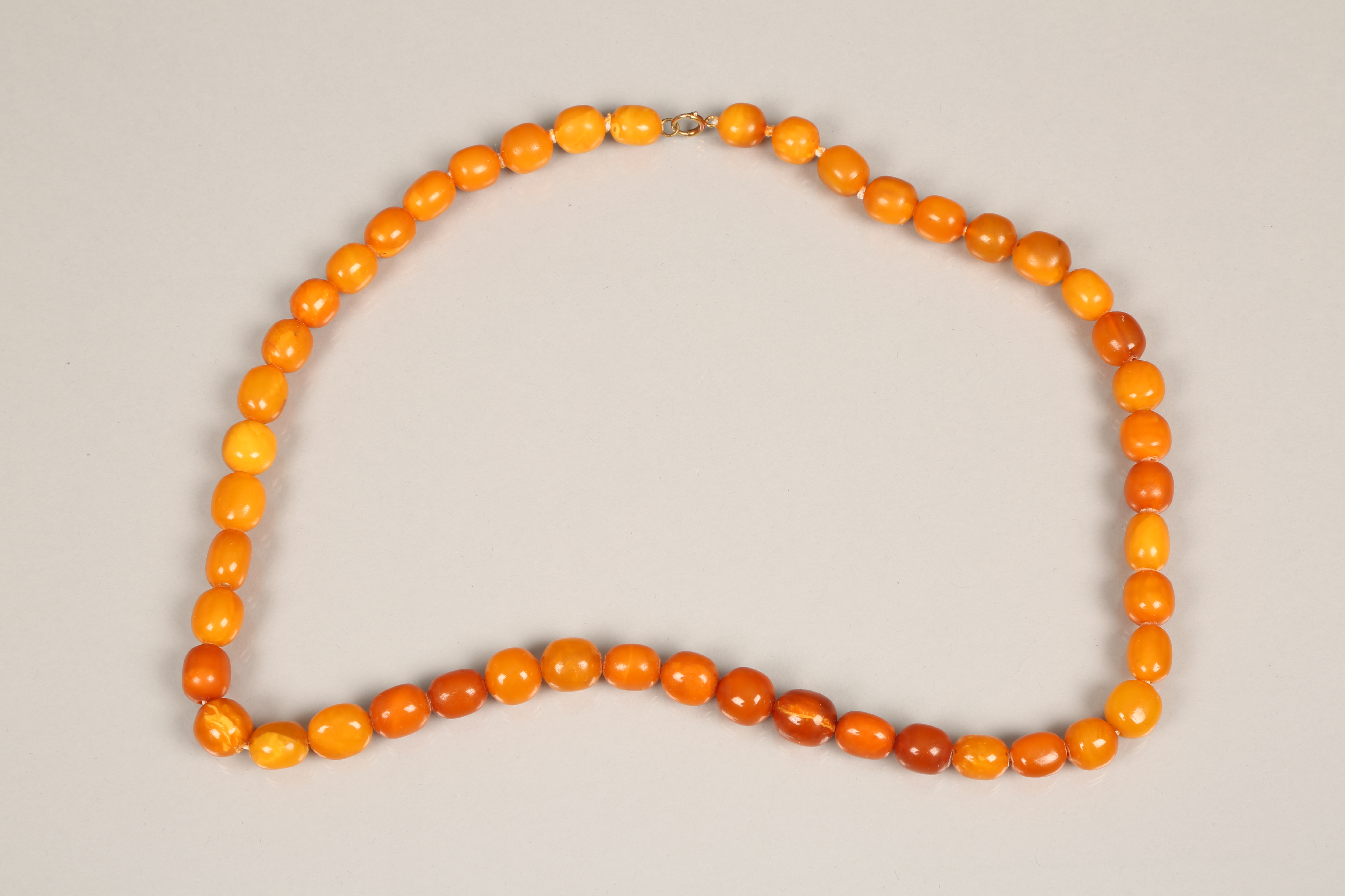String of butterscotch amber beads. 64cm long, largest bead 20mm diameter