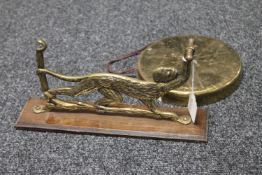 A 20th century brass dinner gong mounted on an board in the form of a monkey