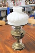An antique brass oil lamp with glass chimney and shade