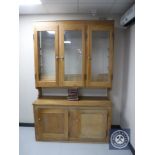 A pine triple door glazed kitchen dresser fitted with cupboards beneath