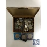 A cigarette box of assorted foreign coins,