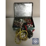 A mid 20th century tin of costume jewellery, beads,