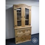 A pine glazed door bookcase fitted with double cupboard and drawers beneath