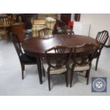 An oval mahogany dining table and six shield back chairs