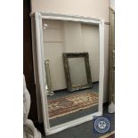 A white swept framed mirror,