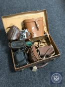 A vintage leather luggage case containing a set of Regent 10 x 50 binoculars,