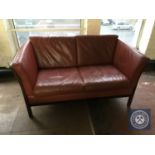 A late twentieth century Danish wooden framed red leather two seater settee