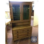 A blonde oak double door leaded glass door bookcase fitted with three drawers beneath
