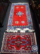 Two fringed woollen rugs on red ground
