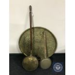 A circular Eastern brass embossed wall plaque and two bed warming pans