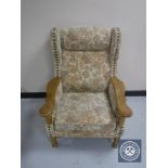 A blonde oak framed wing backed chair upholstered in floral fabric