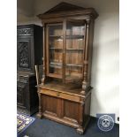 A 19th century oak glazed bookcase with pillar support fitted with cupboard doors