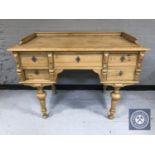 A 20th century pine desk fitted with five drawers on turned legs