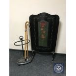 A 20th century hand painted fire screen together with a cast stick stand containing sticks,