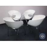 A circular glass topped metal pedestal dining table and four chairs