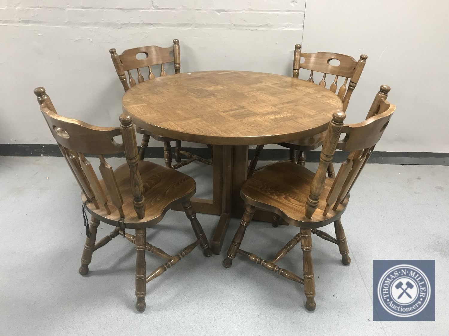 A circular oak pedestal kitchen table together with four chairs