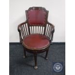 A Victorian mahogany revolving desk chair upholstered in Burgundy leather on club feet