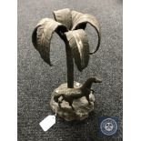 A cast metal figure of a horse standing by a palm tree