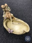 A continental porcelain shallow dish surmounted by two figures,