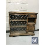 A Priory oak sliding glass door bookcase fitted with a cupboard and drawer