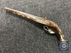 A replica flintlock pistol with mother of pearl inlay