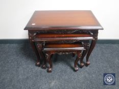 A reproduction nest of three carved tables