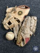 Two leather baseball gloves together with a baseball