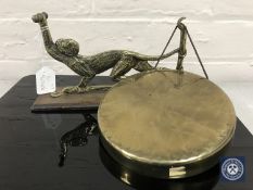 A 20th century brass dinner gong mounted on an board in the form of a monkey