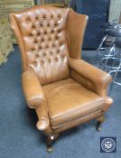 A brown button leather wing back armchair