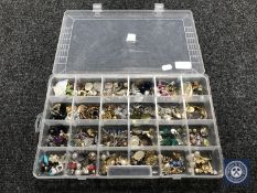 A plastic storage box containing approximately 140 pairs of costume earrings
