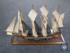 A model of a four masted galleon on a carved wooden board